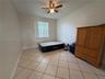 Room featuring light-colored tile flooring, a neutral wall finish, and an integrated ceiling fan with light fixture