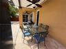 Covered outdoor patio featuring stone-tiled flooring, dual ceiling fans, and a sliding glass door