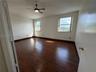 Room featuring wood-finish flooring, two windows with natural light, and a ceiling-mounted fan with integrated lighting