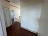 Wood-finish flooring, white louvered closet doors, textured wall finishes, and a staircase with a wooden handrail and balusters