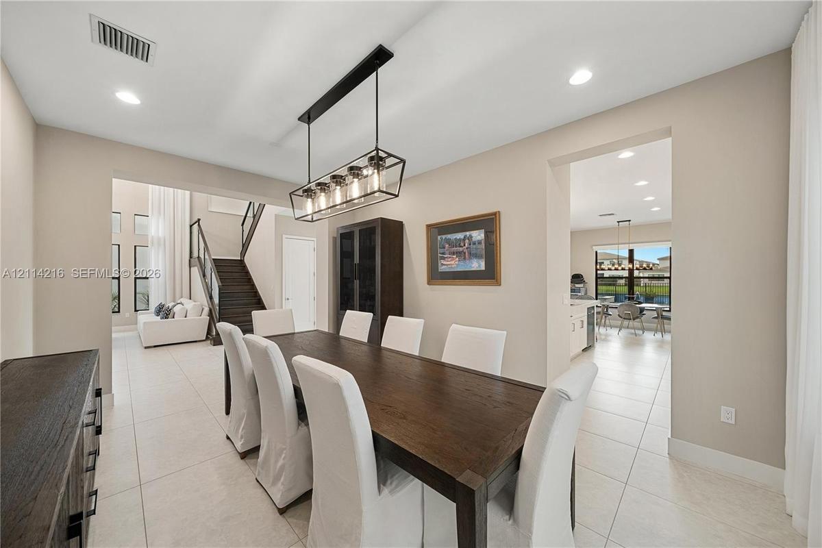 Dining area featuring oversized tile flooring, recessed lighting, and a multi-light linear pendant fixture, including a built-in floor-to-ceiling cabi