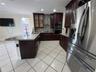 Kitchen featuring dark wood cabinetry, stone-surface countertops, stainless steel appliances, a central island, and recessed lighting