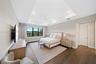 Tray ceiling with recessed lighting, wide-plank wood-finish flooring, and black-framed windows