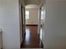 Arched hallway featuring wood-finish flooring and dual mirrored sliding closet doors
