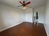 Room featuring wood-finish flooring, dual-door closet, and ceiling fan with integrated lighting
