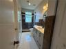 Bathroom featuring a vanity with a light-toned countertop, dark stone wall tiling, a walk-in shower with a glass enclosure, and large-format tile floo