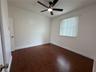 Room featuring wood-finish flooring, a matte black ceiling fan with integrated lighting, and vertical window blinds