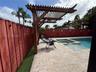 Outdoor area featuring a built-in wooden pergola, stone paver decking, a swimming pool with an integrated spa, and a vertical wood privacy fence