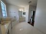 Bathroom featuring a soaking tub, dual-sink vanity with light-tone countertops, polished wall-mounted mirrors, and white ceramic tile flooring