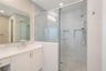 Bathroom featuring a vanity with a light-toned countertop, undermount sink, and integrated cabinetry, paired with a walk-in shower enclosed by glass p