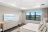 Tray ceiling with recessed lighting and a central ceiling fan, large windows with dark frames, and wood-finish flooring