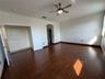Vaulted ceiling with an integrated multi-blade ceiling fan, wood-finish flooring, and arched architectural entryways
