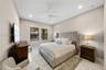 Neutral-toned room featuring high ceilings, recessed lighting, a white ceiling fan, and large windows with dark frames