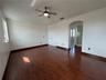 Spacious room featuring wood-finish flooring, vaulted ceilings, and an overhead ceiling fan