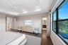 Tray ceiling, wood-finish flooring, ceiling fan, and large windows with exterior water scenery