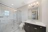 Bathroom featuring a glass-enclosed walk-in shower with stone-patterned tile, dark wood-finish cabinetry, a white countertop with an integrated rectan