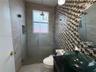 Bathroom featuring a glass vessel sink, dark stone countertop, mosaic tile accent wall, and a walk-in shower with a glass enclosure and recessed niche
