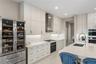 Kitchen featuring white ceiling-height cabinetry, quartz countertops, stainless steel appliance suite including a built-in wine refrigerator, and a ce