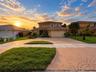 Two-story exterior featuring a decorative paved driveway, tiled roof, and manicured landscaping