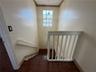 Staircase featuring wood-finish treads, a white spindle balustrade, a singular pendant light fixture, a paneled window, and crown molding