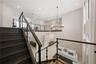Staircase with wood-finish treads, dark railings, and glass panels
