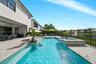 Covered patio with paver flooring, custom in-ground swimming pool, elevated spa with tile finish, and water feature