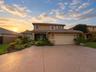 Two-story residence featuring a tile roof, stucco exterior, attached two-car garage, and a decorative stamped concrete driveway surrounded by establis