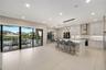 Kitchen featuring shaker-style cabinetry, quartz countertops, a stainless steel range hood, integrated wine storage, and oversized sliding glass doors