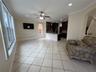 Open concept area featuring large-format ceramic tile flooring, recessed lighting, a ceiling fan, and dark-toned cabinetry with a stone-surfaced break