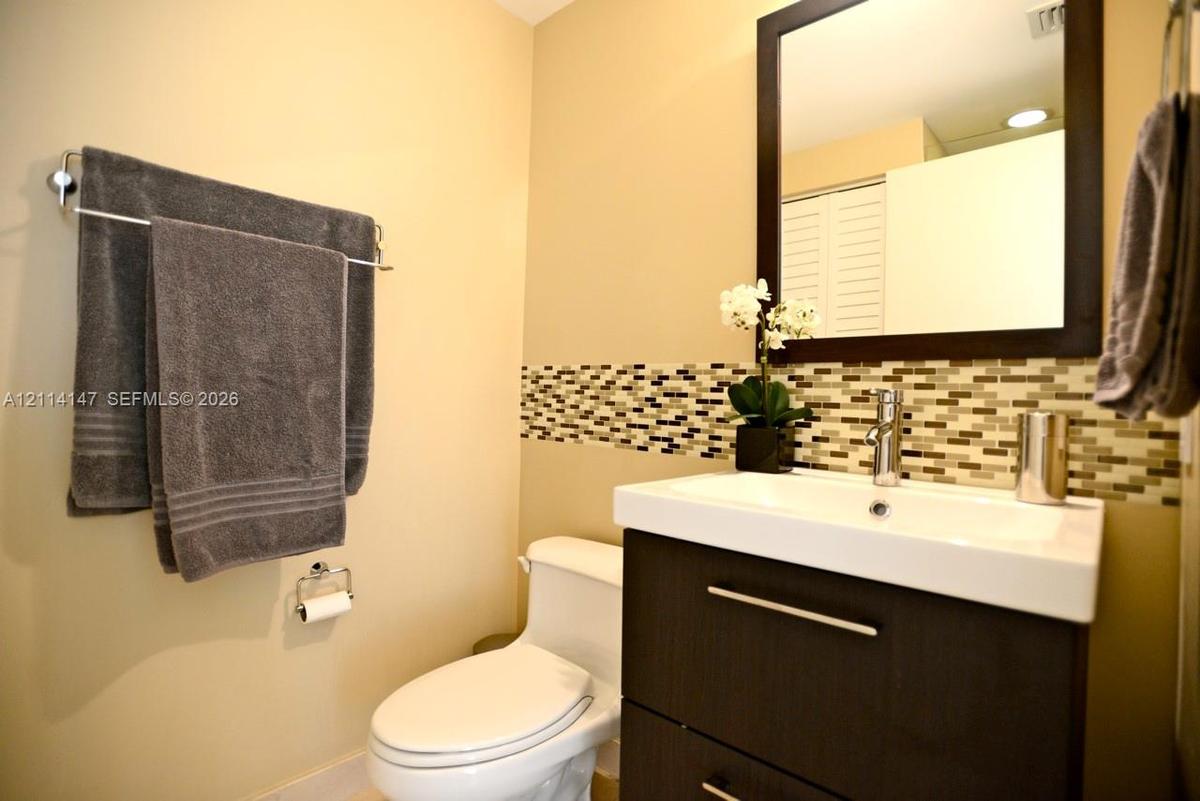 Modern vanity with a rectangular sink, espresso-finish cabinetry, mosaic tile backsplash, and a framed mirror