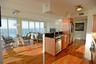 Wood-finish flooring, kitchen island with dark solid-surface countertop, stainless steel appliances, and floor-to-ceiling windows