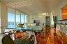 Floor-to-ceiling glass windows, wide-plank wood-finish flooring, custom multi-pendant chandelier, and a built-in breakfast bar