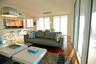 Open-concept floor plan featuring wood-finish flooring, floor-to-ceiling glass sliding doors, built-in cabinetry, and integrated pendant lighting