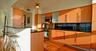 Kitchen featuring wood cabinetry, stainless steel appliances, dark stone-finish countertops, an integrated breakfast bar, and wood-finish flooring