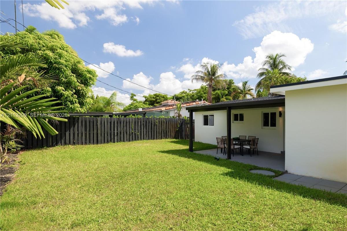 Backyard space featuring a covered patio, manicured lawn, and privacy fencing