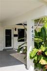 Covered entryway featuring light-toned stone masonry facade, full-glass panel entry door, matte black wall-mounted fixtures, and minimalist vertical a