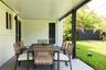 Covered patio featuring a painted concrete floor, recessed lighting, and a dark metal support column overlooking a manicured lawn enclosed by a privac