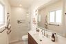 Bathroom featuring a slatted wood-finish vanity with a white countertop, walk-in shower with a glass enclosure and integrated wall niche, and a large 