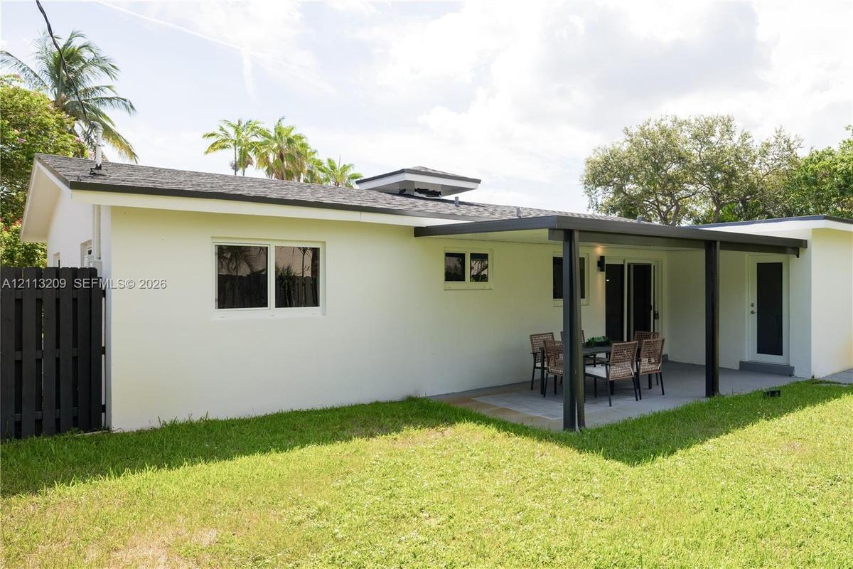 Exterior features include a covered patio, paved hardscaping, a fenced yard, and a shingled roof