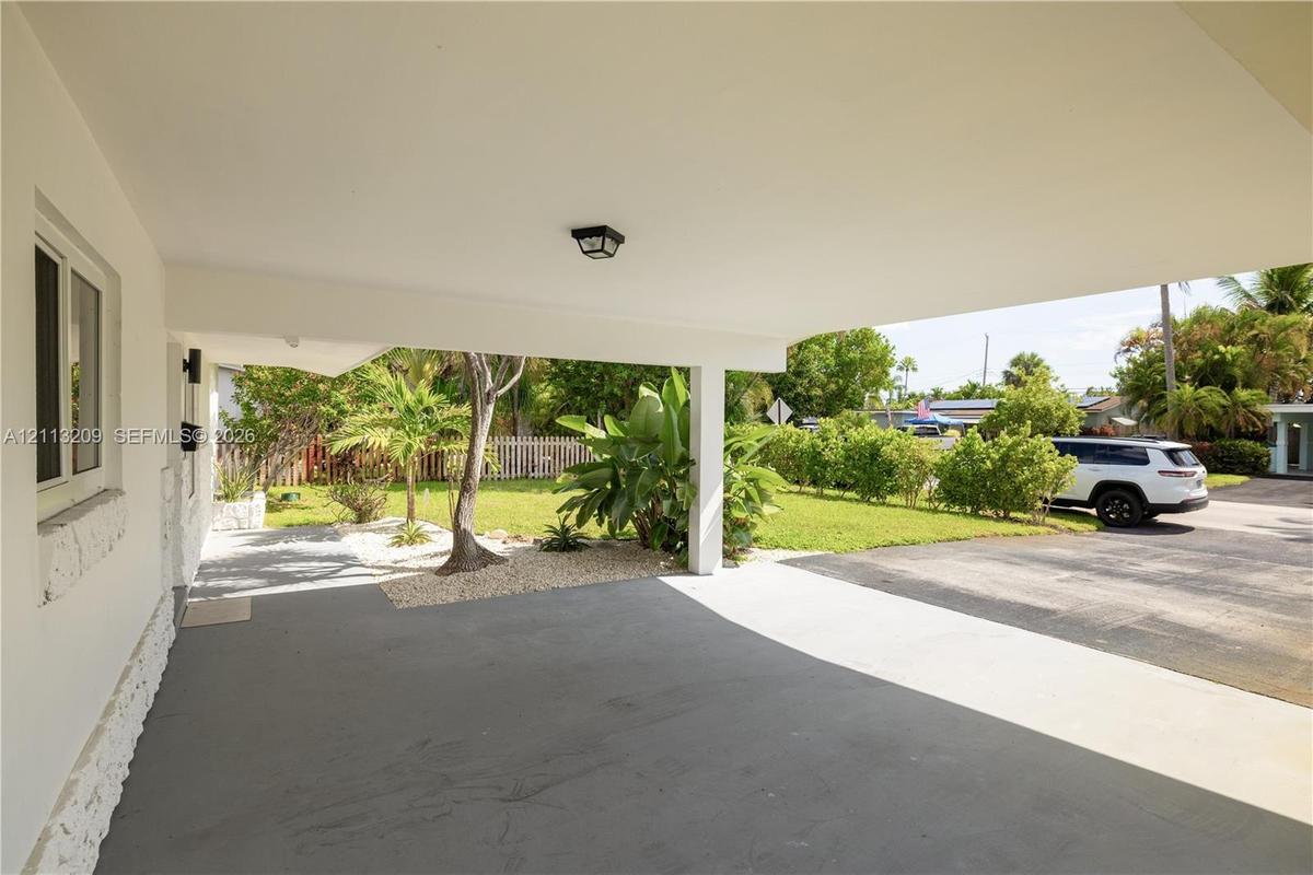 Covered carport with a concrete floor, integrated ceiling lighting, and exposed support pillar