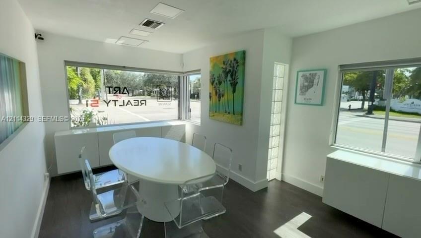Interior space featuring dark-finish flooring, built-in low-profile cabinetry, large picture windows, recessed lighting, and vertical glass block acce