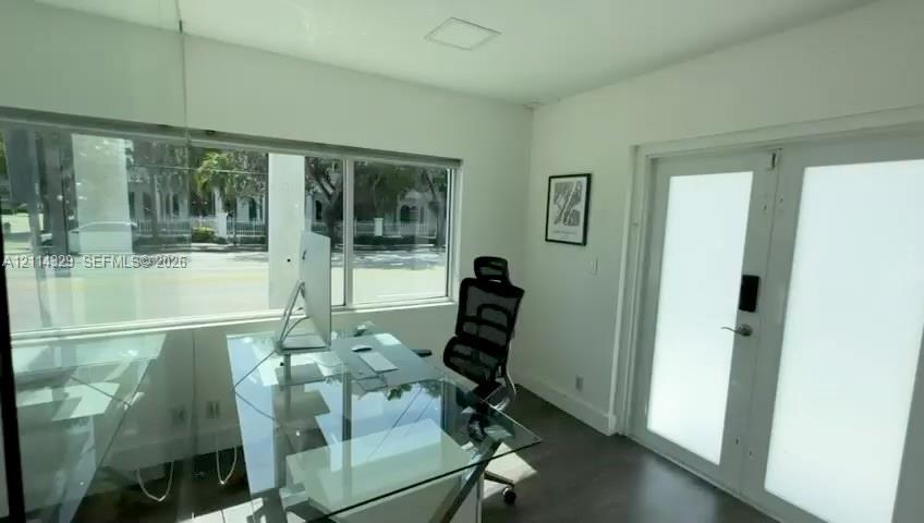 Expansive horizontal windows, dark wood-finish flooring, and white-framed glass pane double doors with frosted privacy panels