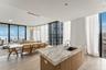 Kitchen island with stone countertop, undermount sink, and textured cabinetry, complemented by floor-to-ceiling glass windows and recessed lighting