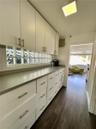 Custom cabinetry with matte metal pulls, solid-surface countertops, glass block backsplash, and wood-finish flooring