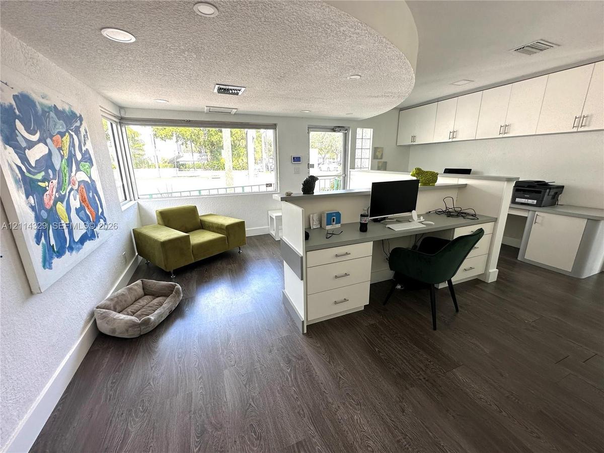 Office space featuring wood-finish flooring, recessed lighting, expansive windows, built-in cabinetry, and a custom desk with drawer storage