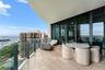 Expansive covered balcony featuring large-format stone-finish flooring, glass panel railing, and full-height sliding glass doors
