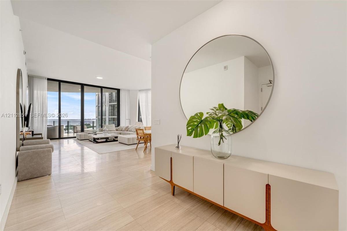 Open-concept interior featuring light-toned tile flooring, recessed ceiling lighting, and floor-to-ceiling glass panel walls
