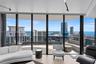Floor-to-ceiling glass walls, curved balcony with structural glass railing, and wood-finish flooring