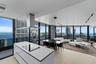 Open-concept kitchen featuring a white center island with a built-in cooktop, stainless steel range hood, floor-to-ceiling windows, light-toned floori