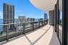 Curved balcony featuring light-toned tile flooring, glass panel railings with metal framing, and full-height sliding glass doors